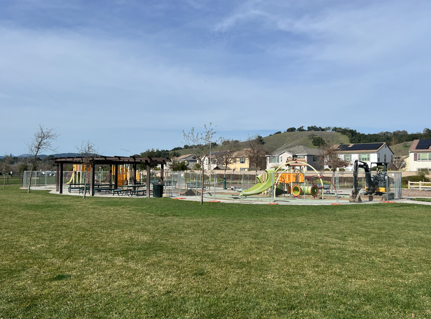 Wide view of Hecker Pass Park showing a playground area with fencing